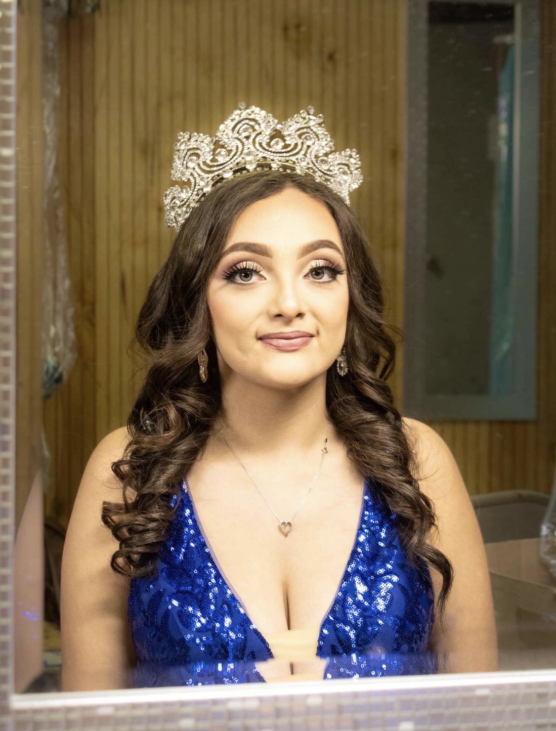 Event glam makeup with a champagne eye, lashes, and rosy lip, finished with a crown and soft curls