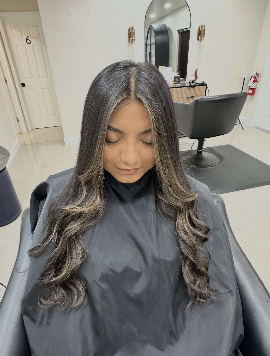 Dark brunette hair with blonde face-framing highlights in soft glam waves